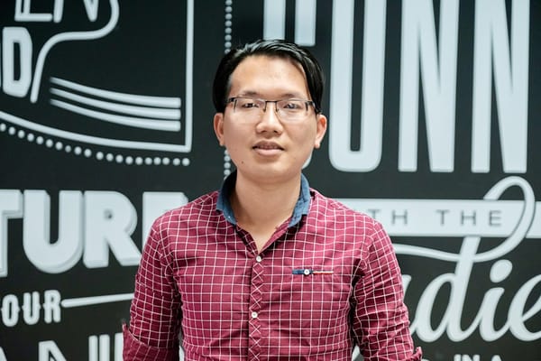 a man wearing glasses standing in front of a sign